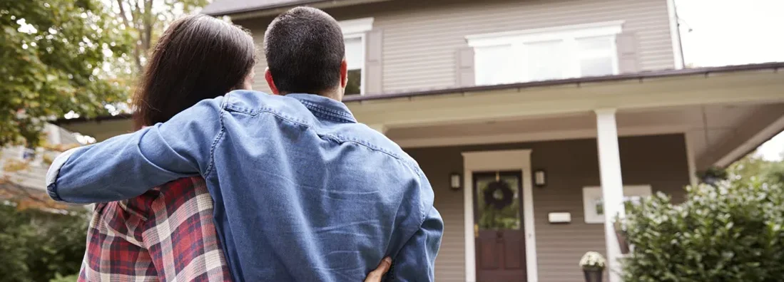 Rear View Of Loving Couple Looking At House. Top 12 Things You Wish You Knew Before Buying Your First House.