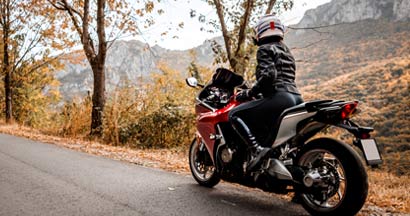 Female biker enjoys view in nature. Motorcycle Insurance Discounts.
