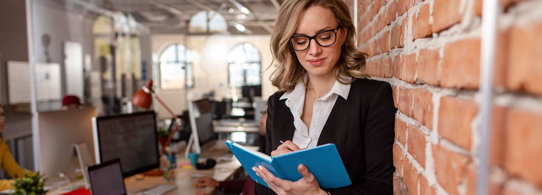 Woman at her workplace, writing something down. Find Cincinnati Ohio Business Insurance.