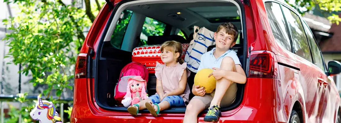 Kids sitting in car trunk before leaving for summer vacation with parents. How to Find the Best Car Insurance in Madison, Mississippi.