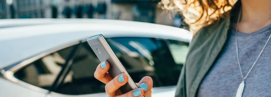 Woman using smart phone standing on street. My Insurance Rates in West Virginia Went Up! What Should I Do?