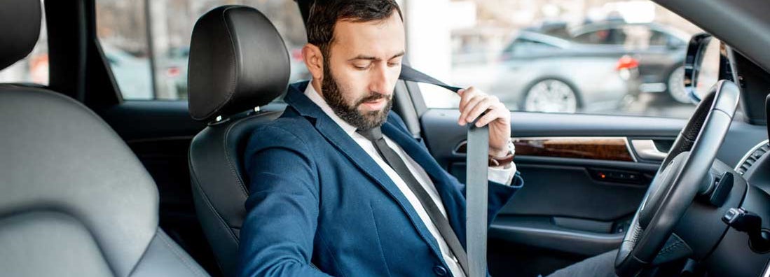 Businessman fastening car safe belt. Find Baltimore Maryland car insurance.