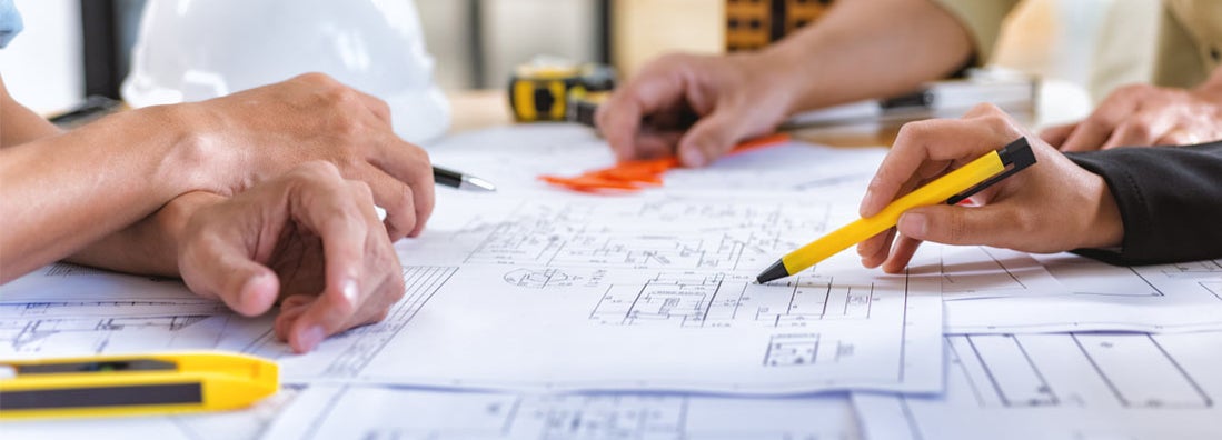 Architect checks construction blueprints on new project with tools at desk in office.