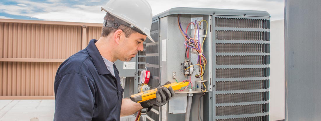 HVAC Tech working on a condensing unit. Find HVAC license requirements by state.