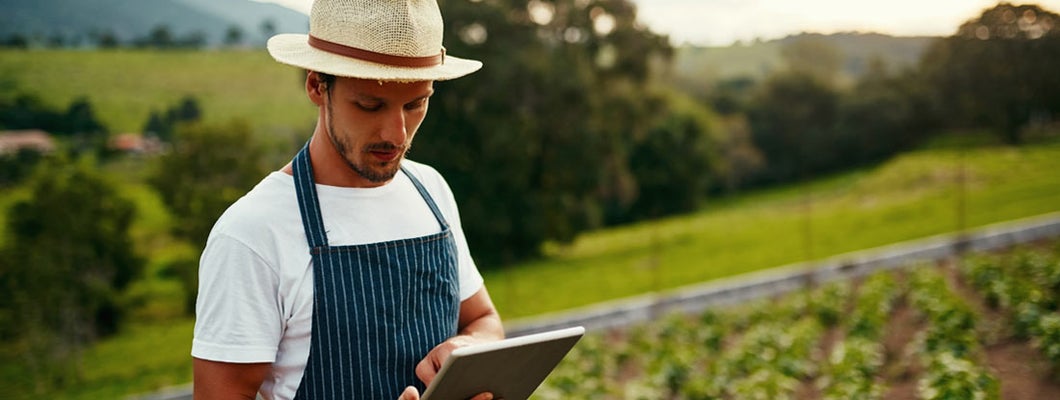 Man using a tablet while working on his hobby farm. What are the best hobby arm insurance companies.