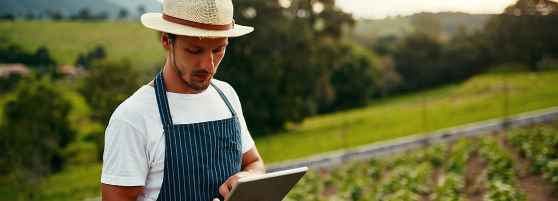 Man using a tablet while working on his hobby farm. What are the best hobby arm insurance companies.