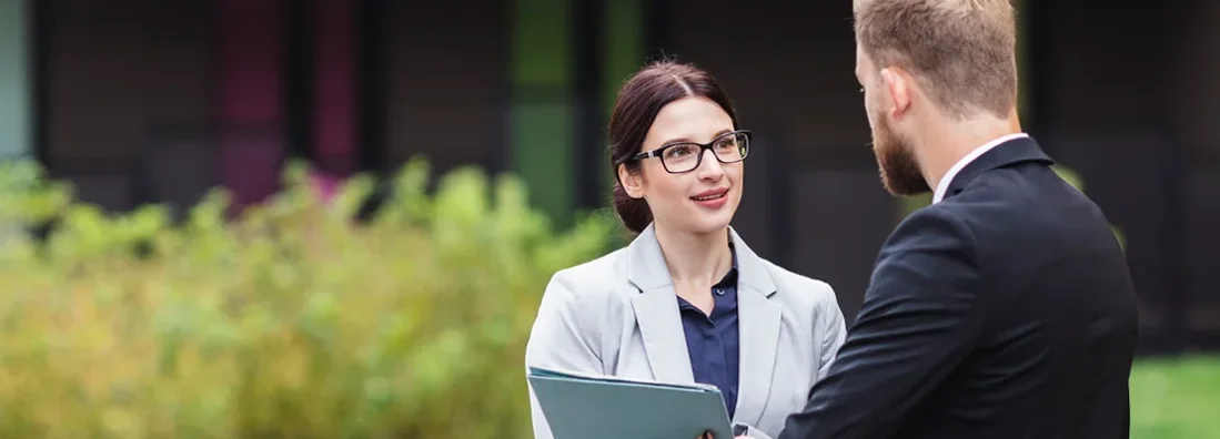 Landlord discussing terms with tenant in front of a residential building. Find Pennsylvania landlord insurance.