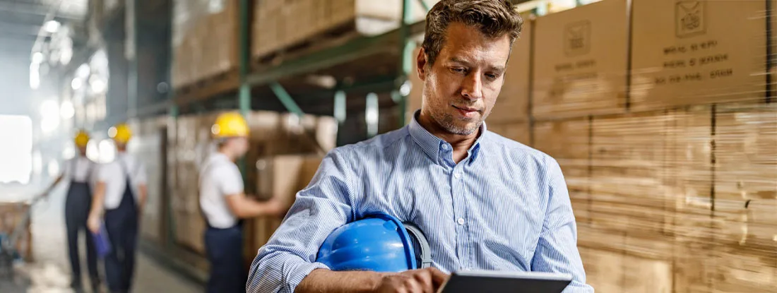 Mid adult warehouse manager using touchpad in a storage room. Workers' Compensation vs. General Liability Insurance.
