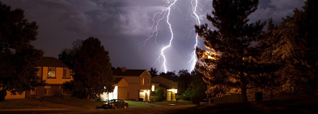 Lightning bolt and thunderhead storms over Denver neighborhood homes. Does insurance cover lightning strikes?