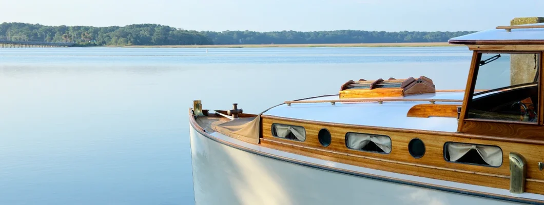 Partial view of a wooden boat cabin anchored in a harbor. Find boat insurance for older boats.