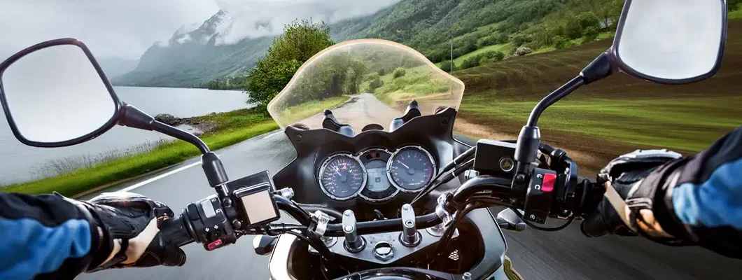 Biker rides a motorcycle in the rain. Find Motorcycle Insurance.