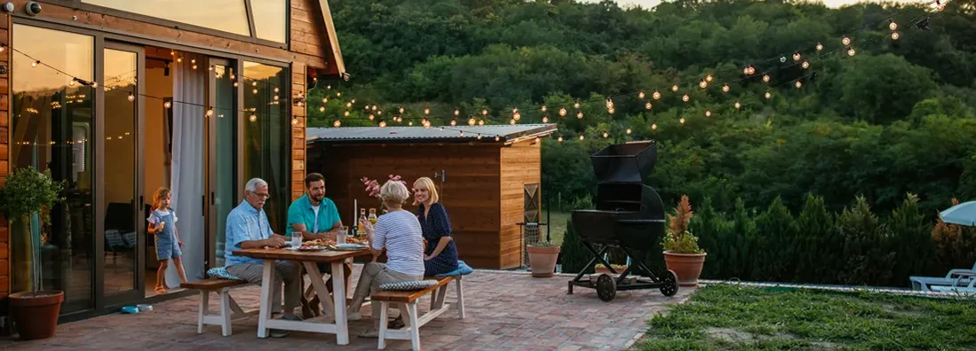 Family dinner around dining table in the backyard. York, Maine Homeowners Insurance.