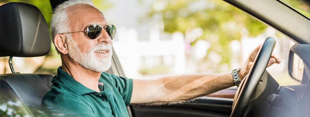 Senior man enjoying a ride in his new car and listening to music. Find Dallas Texas car insurance.