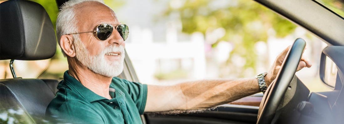 Senior man enjoying a ride in his new car and listening to music. Find Dallas Texas car insurance.