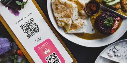 Une assiette de nourriture à côté d'un menu avec un code QR