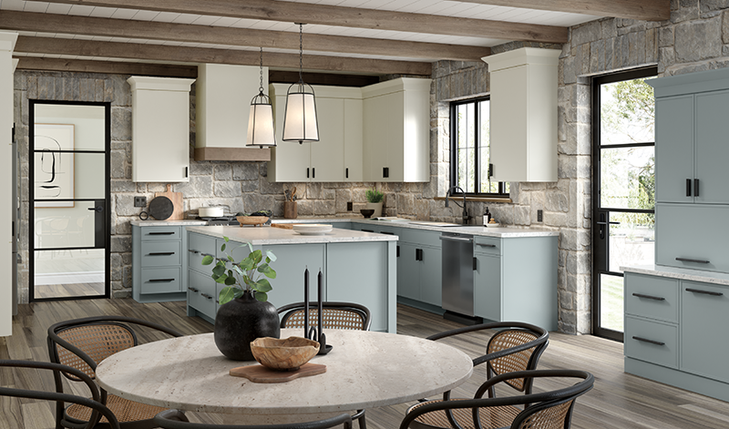 A kitchen with light blue lower kitchen cabinets, off-white upper cabinets, stone walls, and a dining table.
