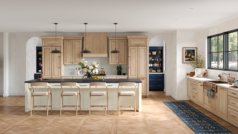 A kitchen with light wood stained cabinets, light wood floors, and a white kitchen island.