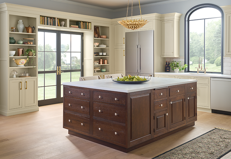 A kitchen surrounded by windows and glass doors featuring a large brown wood island and off-white cabinets.