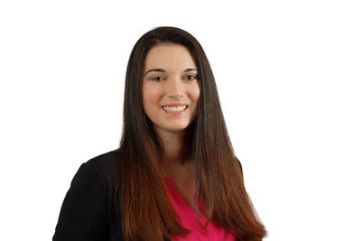 Woman with long brown hair wearing a red blouse smiling at camera.