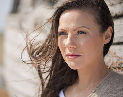 Pretty young woman looks toward the shining sun with her hair blowing.