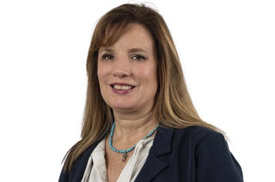 Professional woman with blue beaded necklace wears a black jacket.
