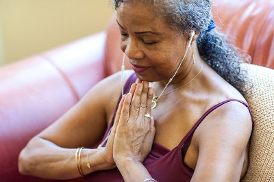 Black woman sits in pray hands meditating.