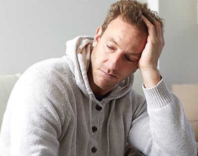 A troubled man holds his heal in deep thought.
