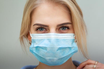 Woman with blonde hair wearing a clinical mask.