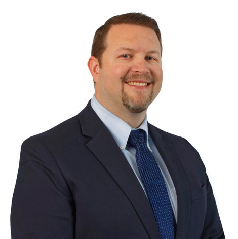 Man wearing blue suit and tie smiling at camera.
