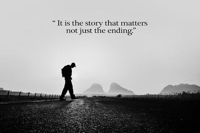 Silhouette. of man walking on road wearing a backpack and looking down.