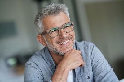 Gray haired white man with glasses smiles.