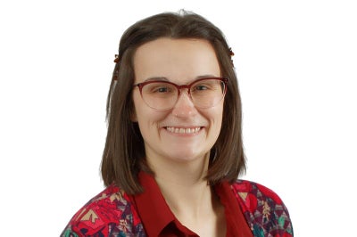 Young woman with glasses smiles at camera.
