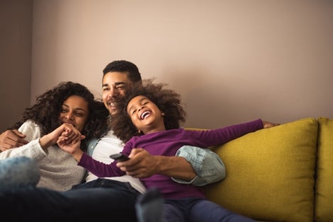 A man with daughters having fun sitting on couch.