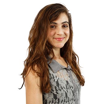 Young woman with long wavy brown hair in a gray top.