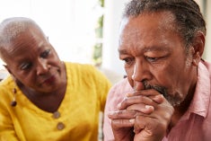 Older African american man looks anxious and worried as an African american woman (possibly his wife) leans in and looks at him concerned.
