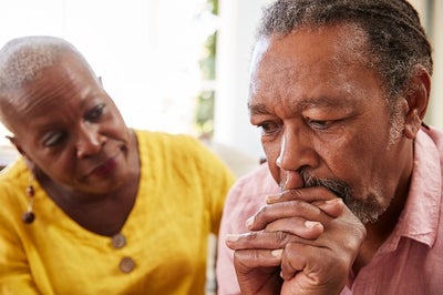 Older African american man looks anxious and worried as an African american woman (possibly his wife) leans in and looks at him concerned.