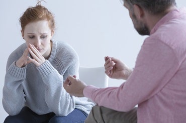 Counselor talking to young lady who is worried and possibly experiencing mental illness such as depression or anxiety.