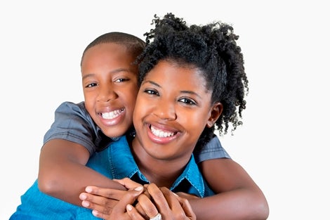 This photo depicts a young boy and woman embracing and smiling.