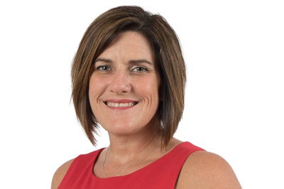 Woman with short hair and red dress smiles at camera.
