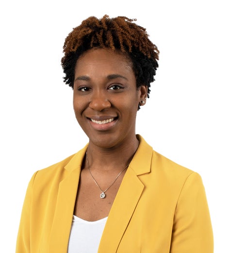 Young African American woman smiling at the camera wearing a bright yellow blazer.