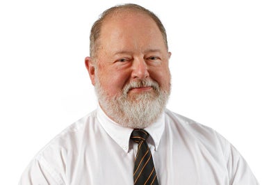 Man with beard wearing a tie smiles at camera.