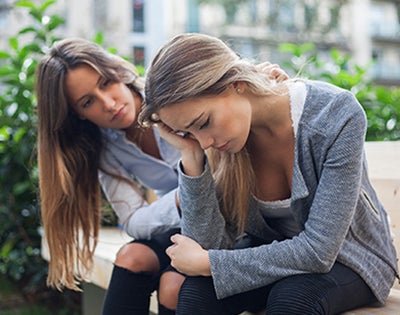 A young woman comforts a depressed female friend.