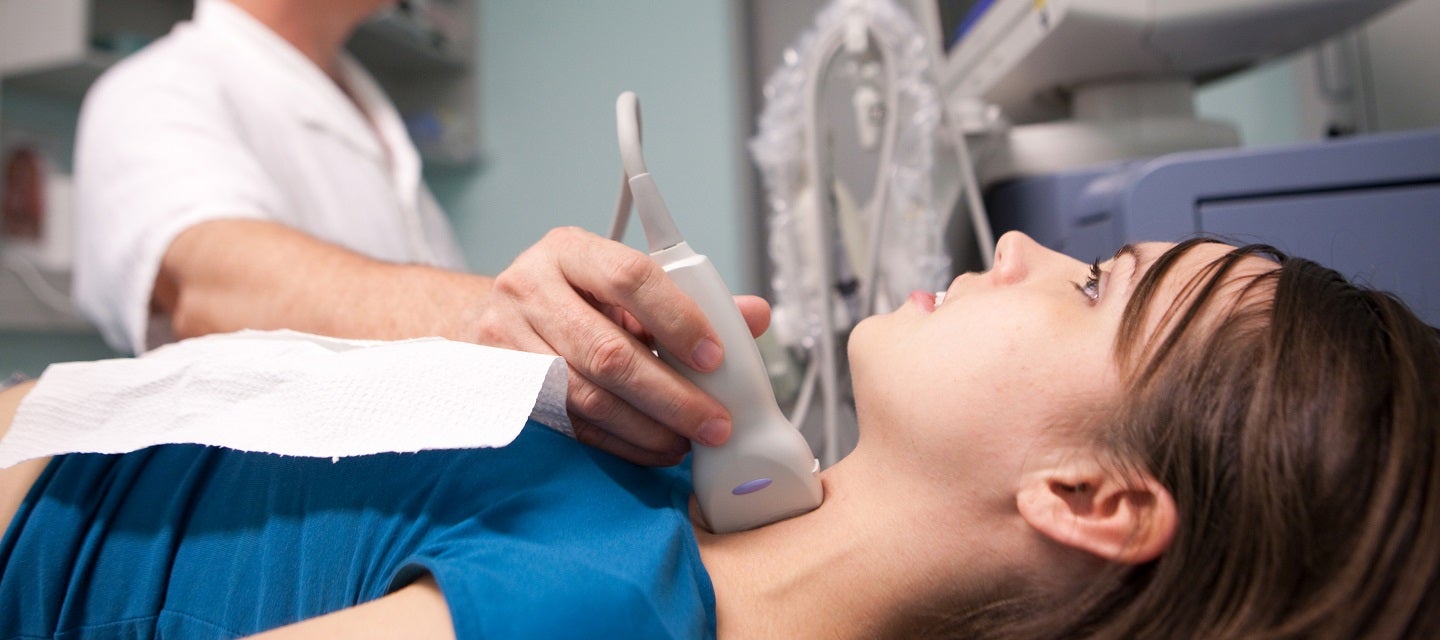 Young woman having ultrasound test on thryroid