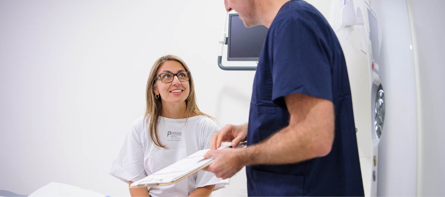 Patient smiling at the technician holding a clip board