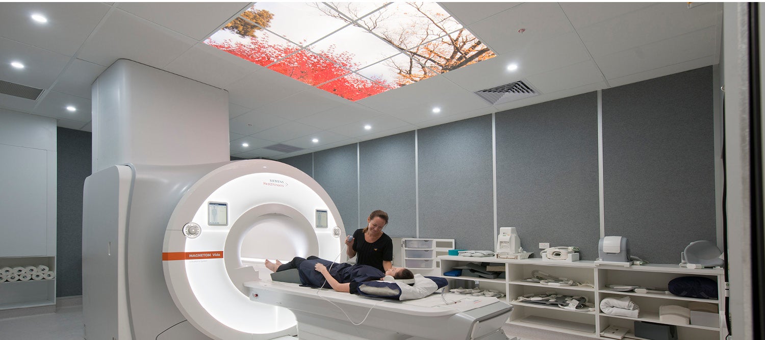 A patient laying on an MRI bed with a technician talking to them