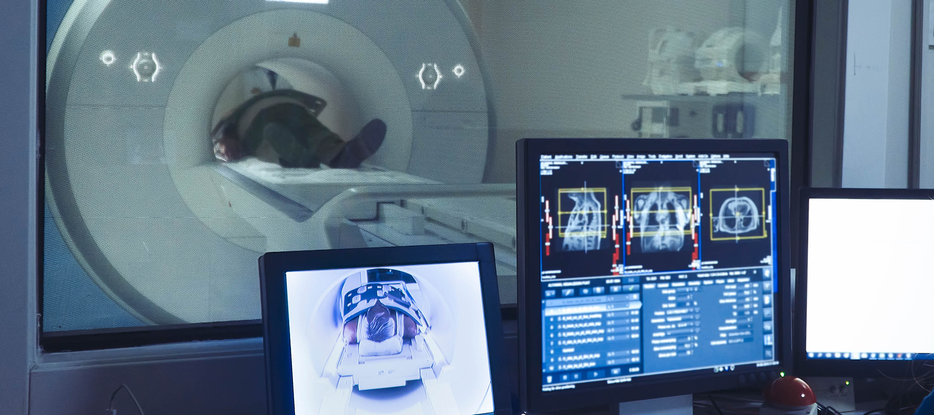 Patient inside CT machine and computer screens displaying images