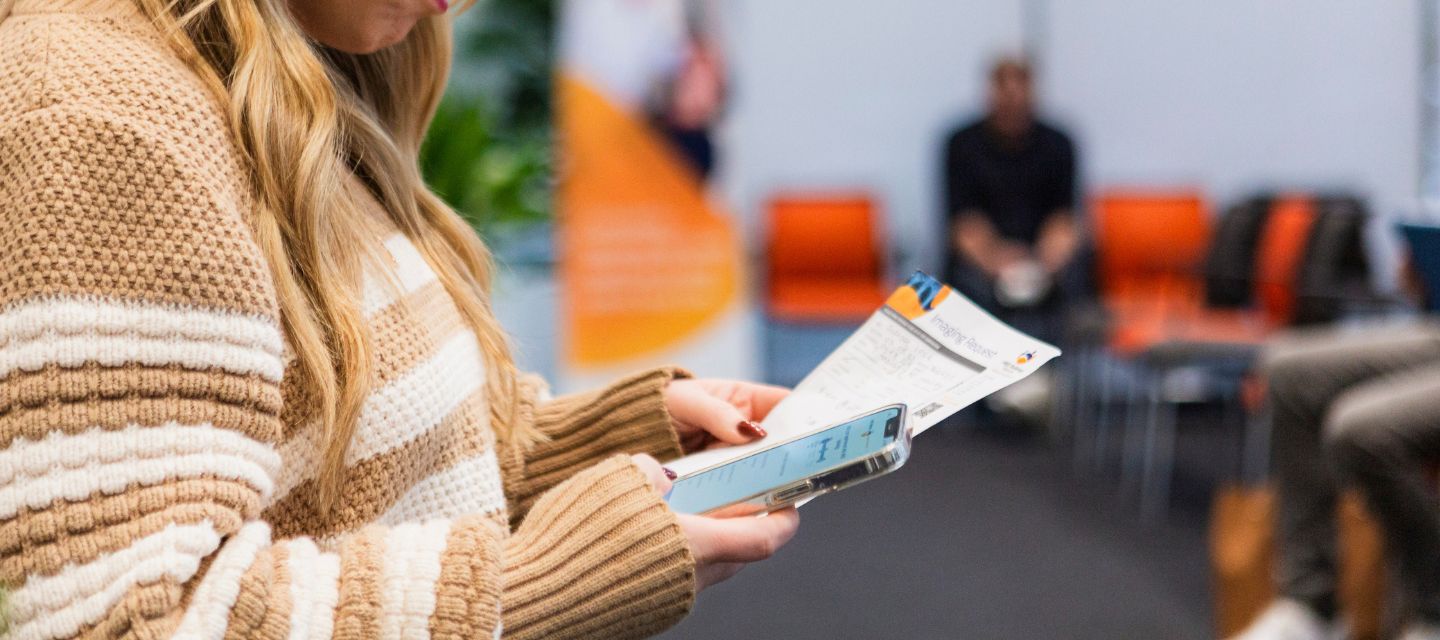 Image of patient holding radiology referral and mobile