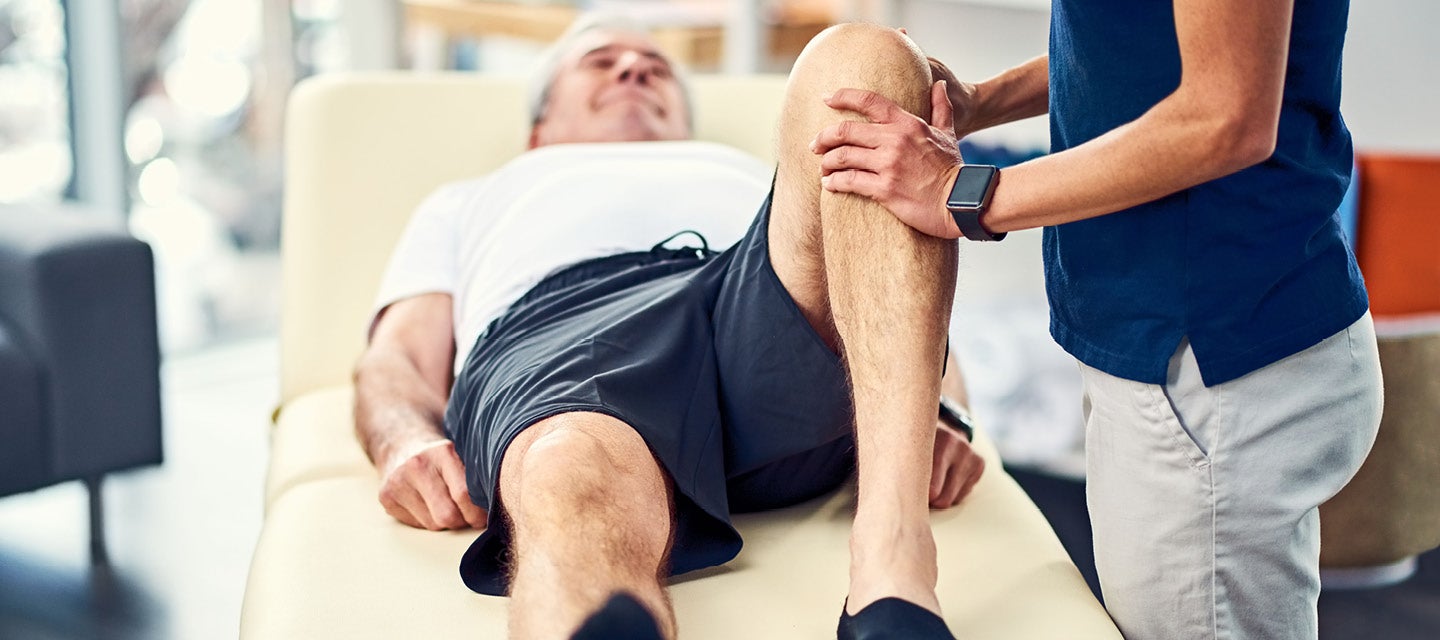 Man laying down having left knee examined 