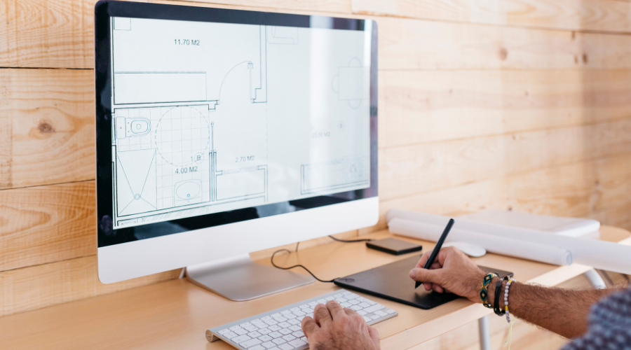 Person working on floor plans displayed on a desktop monitor.