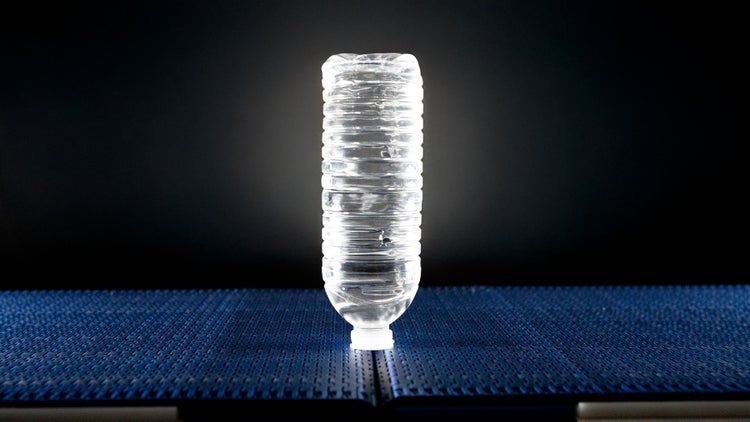 Umgedrehte Wasserflasche, die zwischen zwei Flush Grid-Bändern der Serie 570 transportiert wird